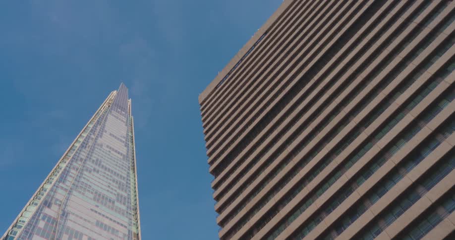 Upward view of two large modern buildings against a blue sky