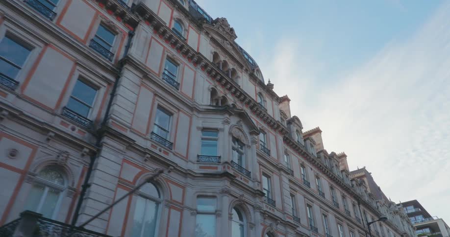 A classic architectural building with ornate detailing and multiple windows stands against a clear sky