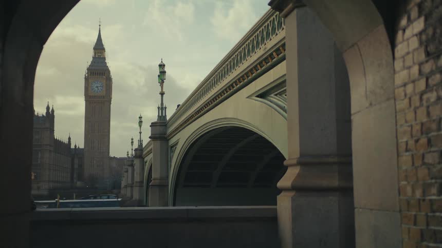 View of a bridge and a tunnel with a boat passing by and the london clock tower in the background