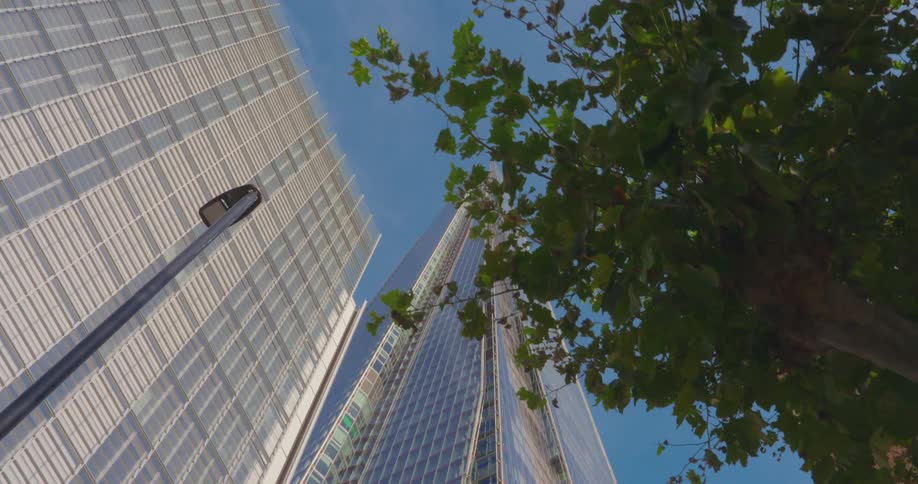 Upward view of a large building mirrored against a blue sky