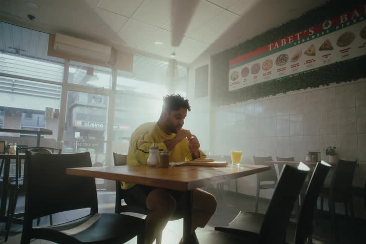 Man eating sandwich sitting at a table in a restaurant