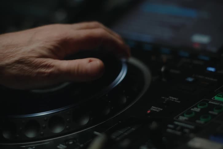 Close up of the hand of a dj manipulating a control on a mixer
