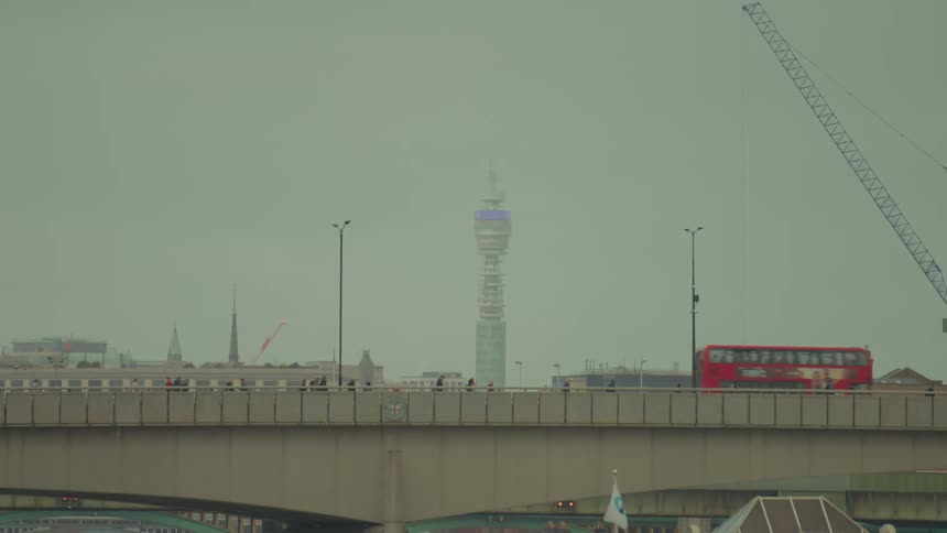 A bridge that goes over the water and there are several people walking and a red bus passing over it