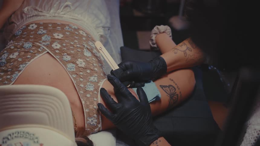 Woman tattooing a clients arm