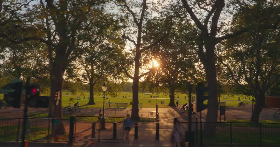 Aerial view of a serene park scene during sunset with warm glow and elongated shadows on the grass