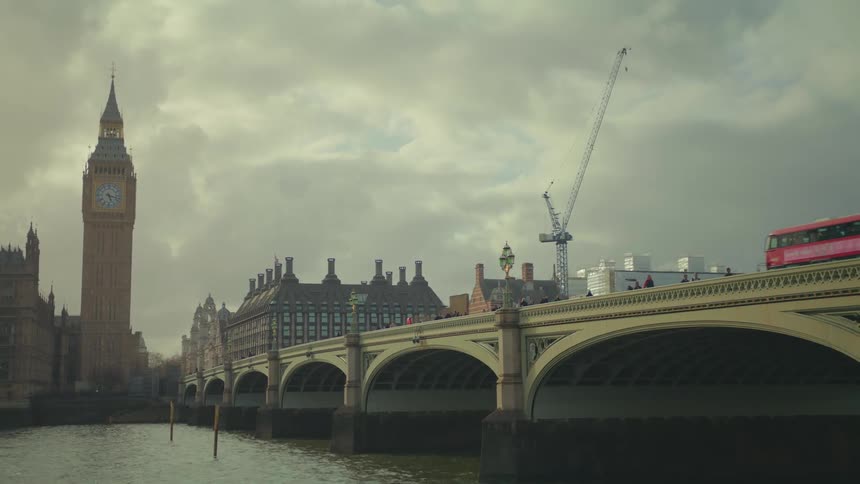 London bridge with a bus passing by a tower in the background