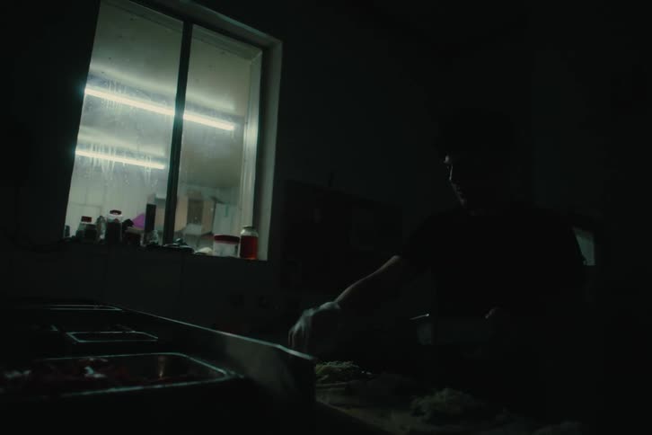 A person cooking pastries on a dark kitchen at dawn