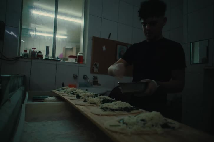 Man inside a restaurant putting cheese on top of pasta