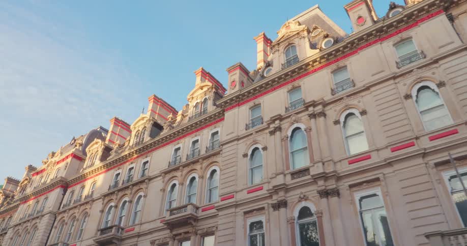 The facade of a beige building with red details and many apartment windows