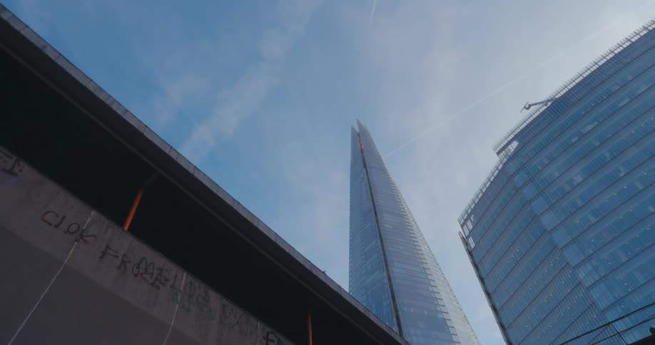 Traveling under an underpass with tall buildings and blue sky above