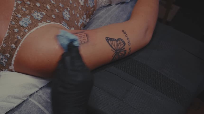 Hand with gloves rubbing alcohol on a cloth at a tattoo service on a person