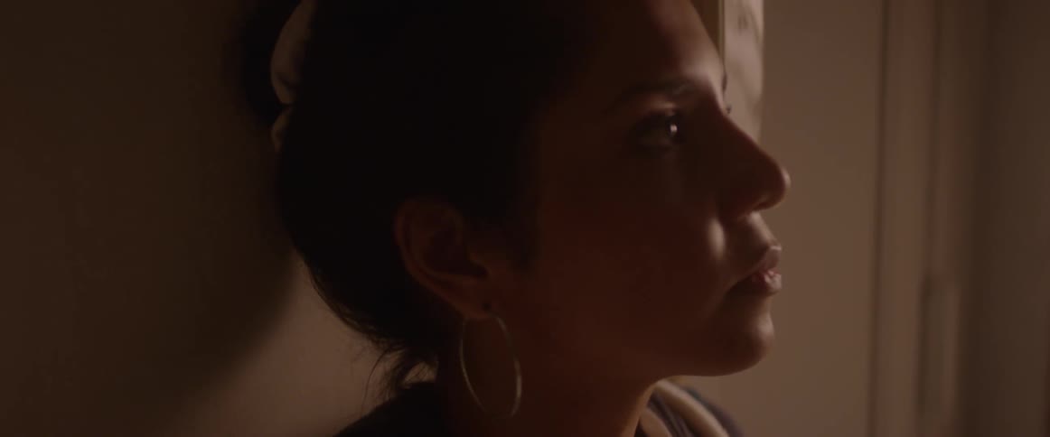 Woman with closed eyes leans against a wall and opens eyes