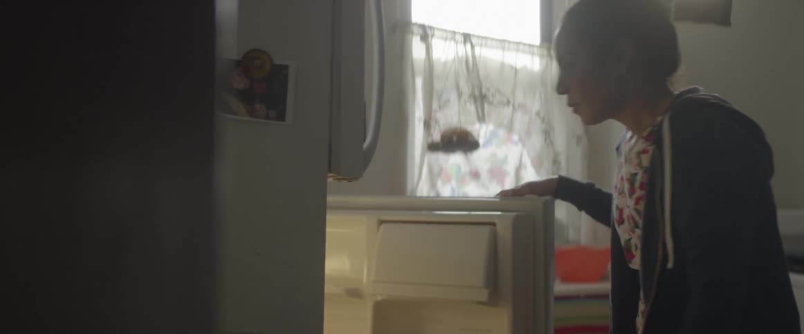 A woman looks in her fridge for food