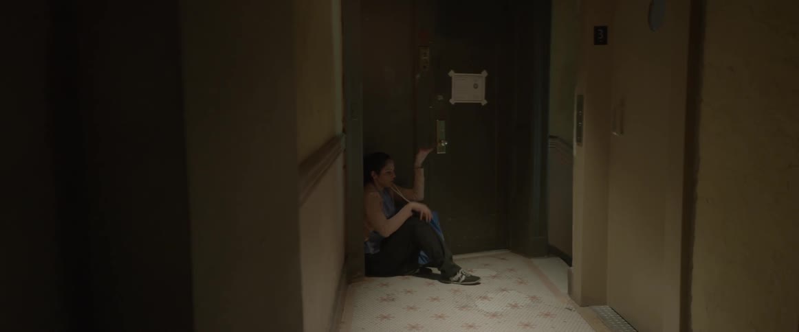 A woman slides down and sits with her head in her hands