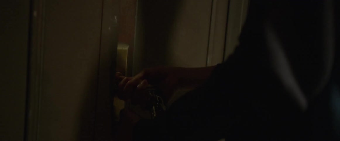 A woman turns her keys in a lock and pushes open a door