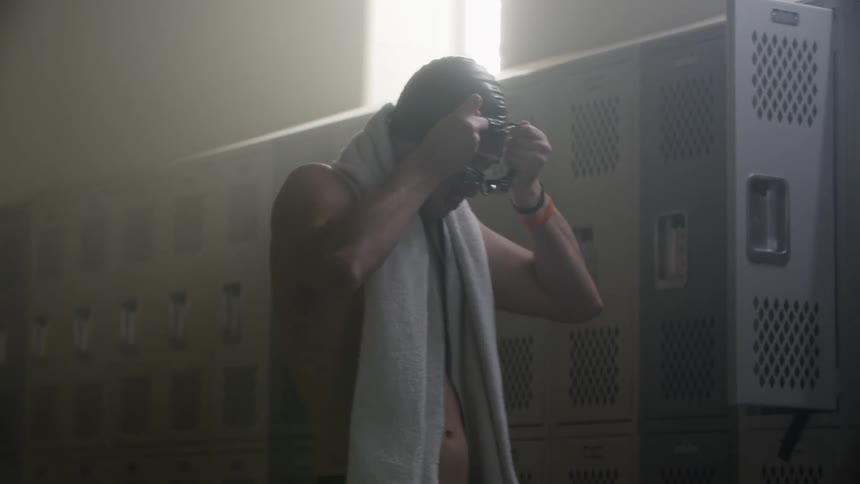 A swimmer puts on his goggles in the locker room