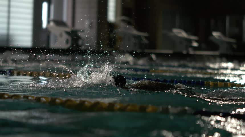 A person is swimming in a lane of a pool and doing the front crawl