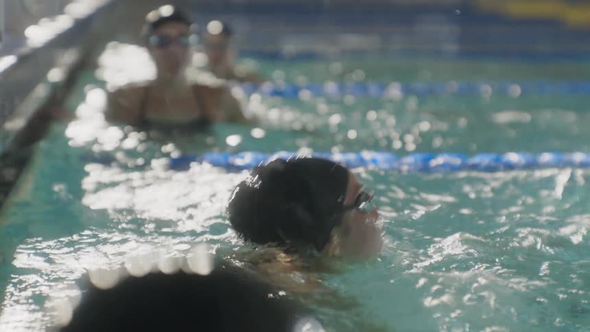 Women reaching the end of the lane in the corner of the pool