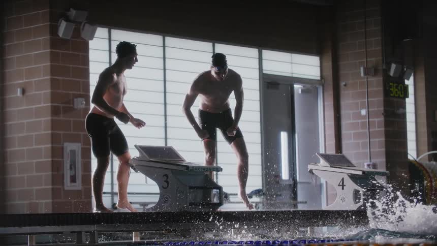 Two men celebrating and cheering as the swimmer reaches the end of the pool lane