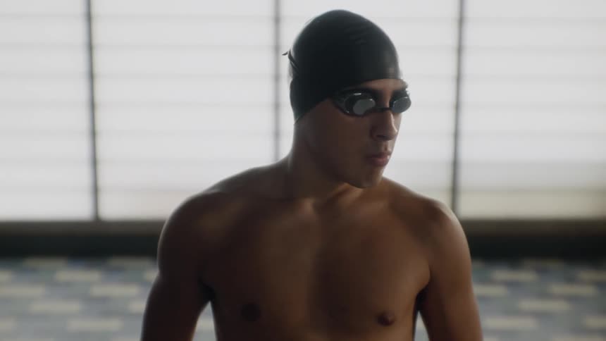 Man with glasses and swimming cap concentrating stretching his arms