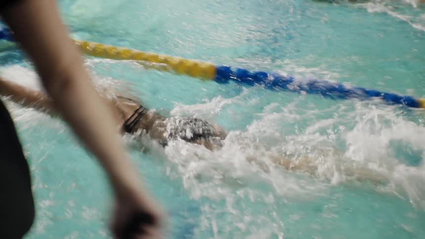 Woman walking and encouraging women who are swimming in the lanes around the pool