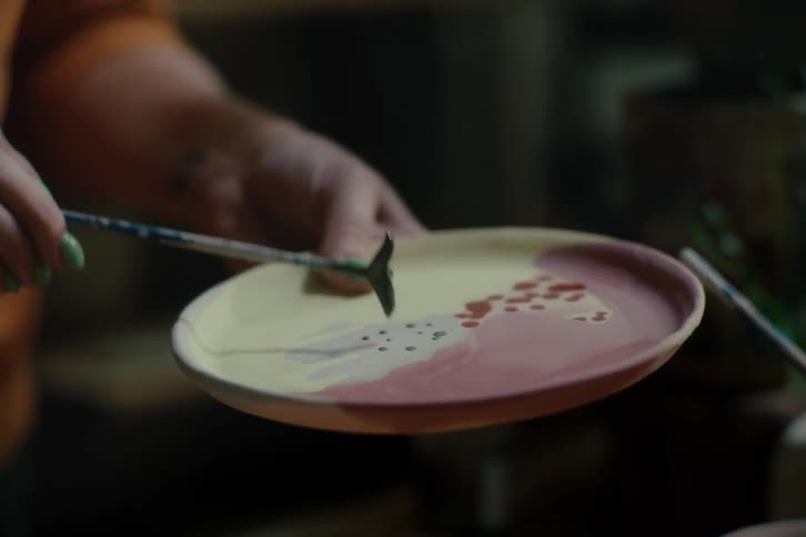 Hands holding a paintbrush and painting a plate