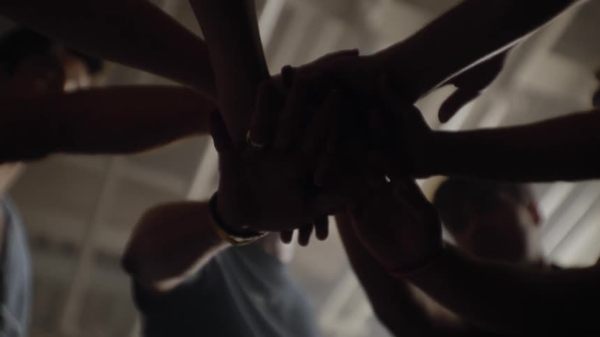A team huddles together hands interlocked for a pep talk in the locker room