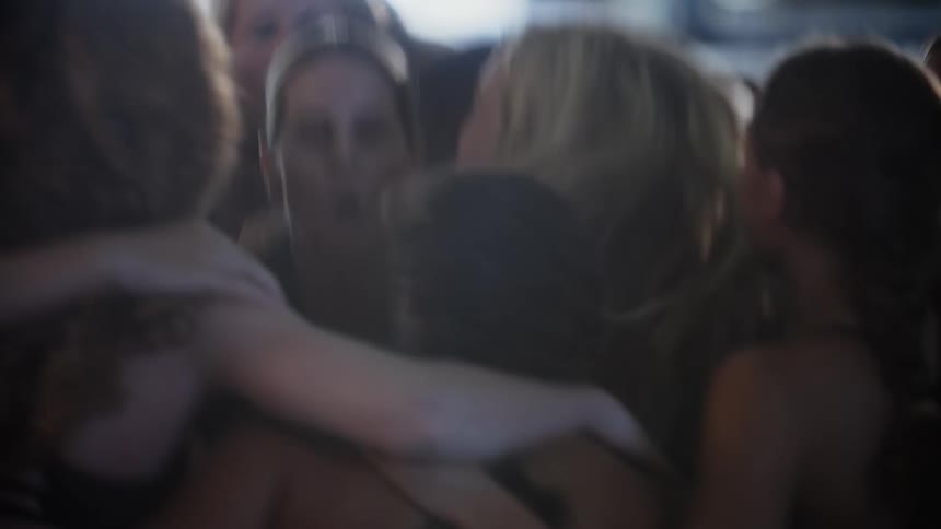Group of female swimmers hugging each other celebrating next to the pool