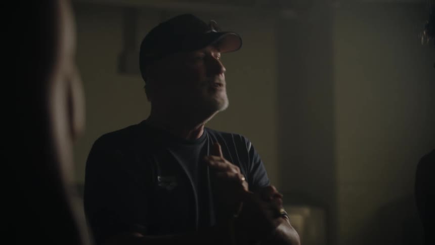 A coach delivers a pep talk to a group of young athletes in a locker room