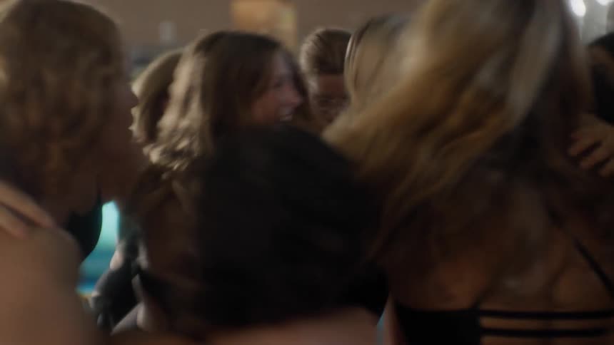 A group of several women are hugging and jumping happily and then they all raise their arms up