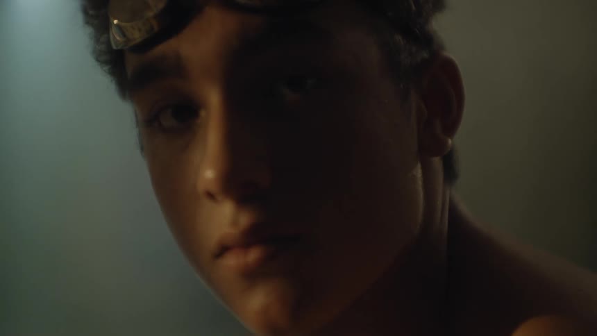 Close up of the face of a young man wearing swimming goggles in a dimly lit room