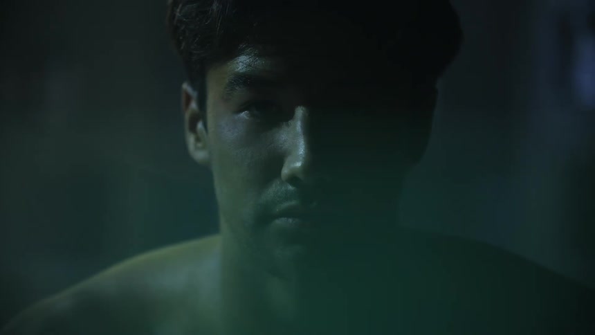 Portrait of a shirtless man sitting in the locker room with water reflection on his face