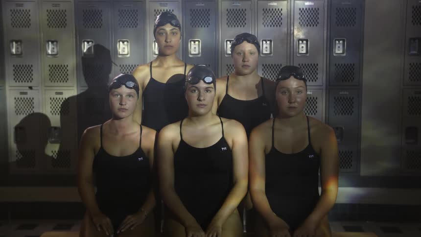 Women sitting in changing room with black swimsuit and water reflection