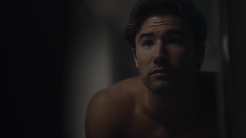 Shirtless man looking at himself in the mirror