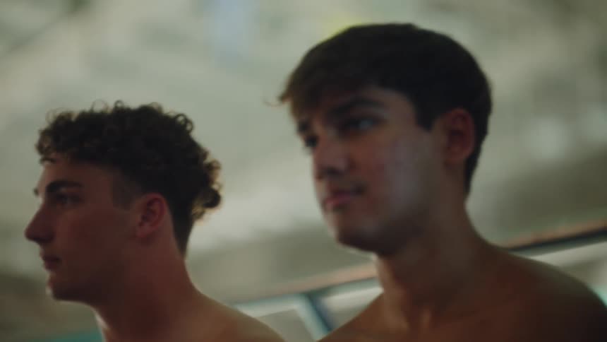 Four young teenagers standing side by side without shirts in an indoor setting