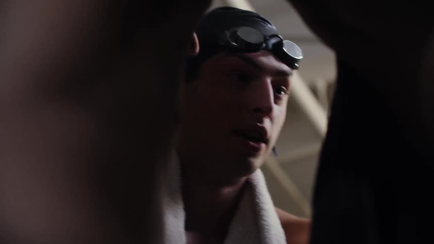 Swimming teammates talk together in a huddle in the natatorium