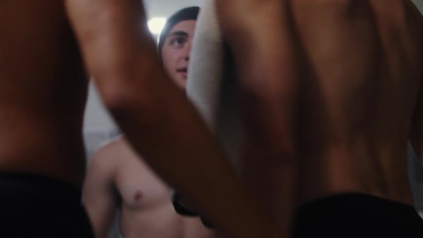 Male swimmers hugging each other cheering and leaving the locker room