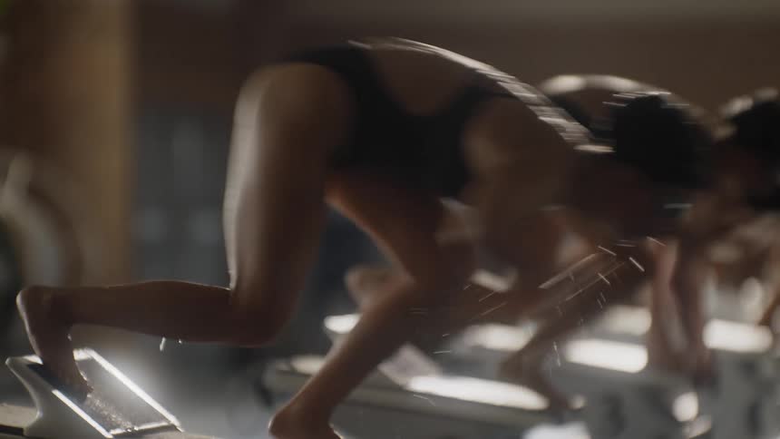 Swimmers in starting position jumping into the pool