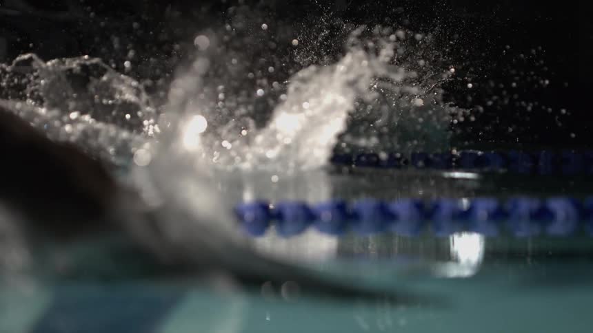 Two swimmers in position jumping and diving into a pool