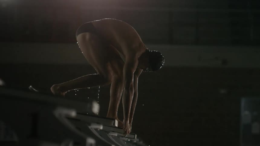 A man is in position to dive into the pool