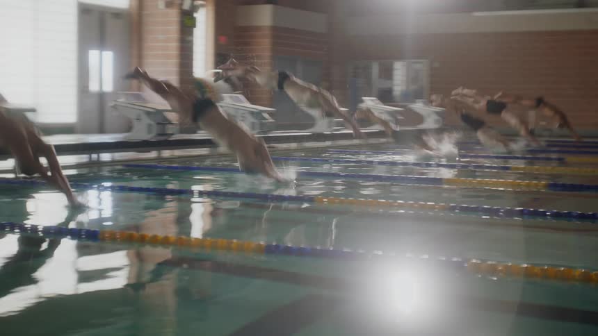 Group of young swimmers jumping into the pool in their respective lanes