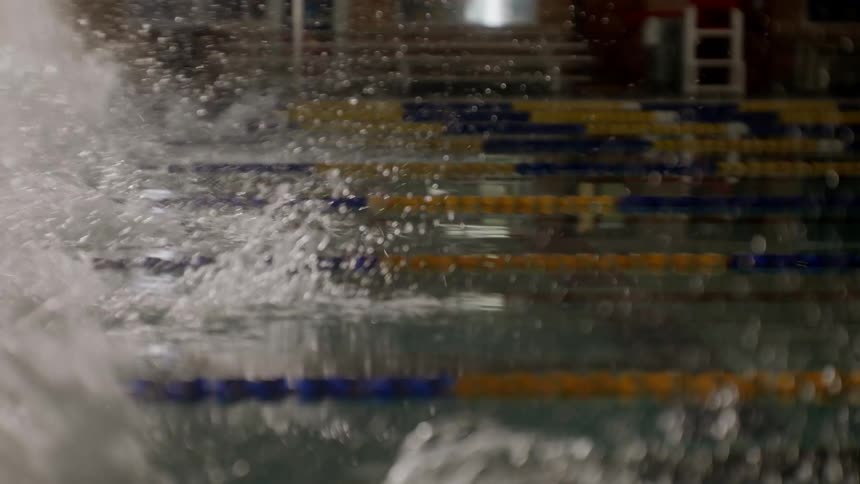 Men are competing as they swim in the pool