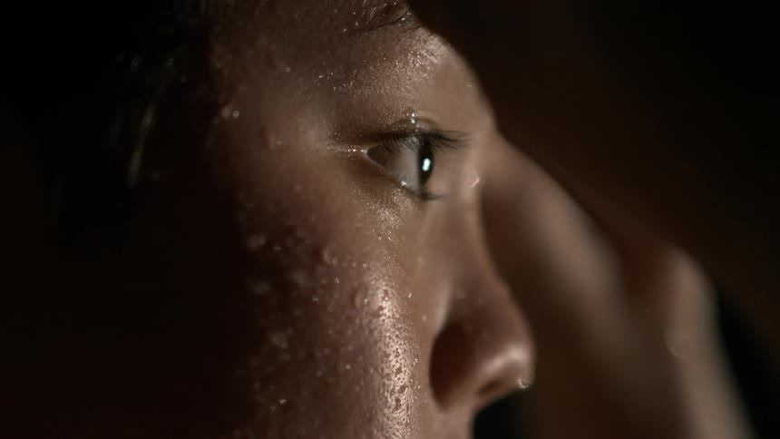 Close up of a young womans face with water droplets and a determined expression