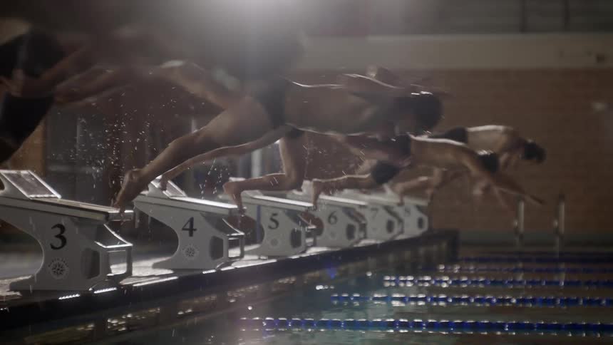 Swimmers dive into the pool for a race