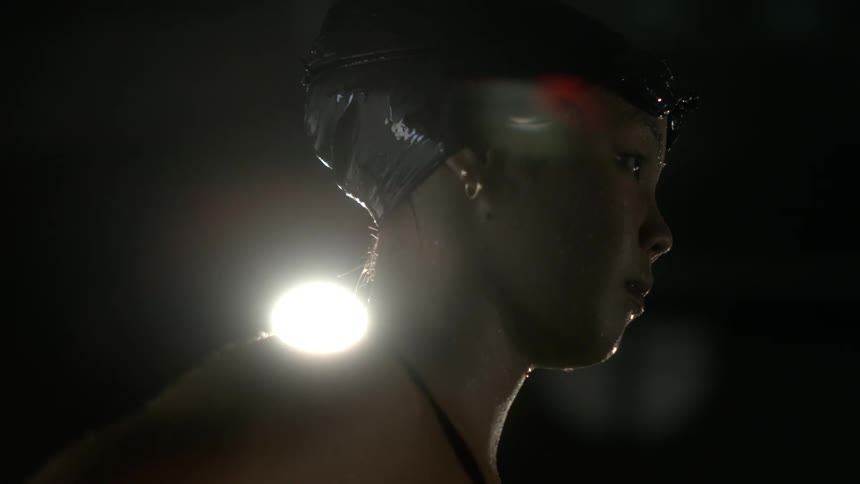 Side portrait of a female swimmer with goggles and cap concentrating