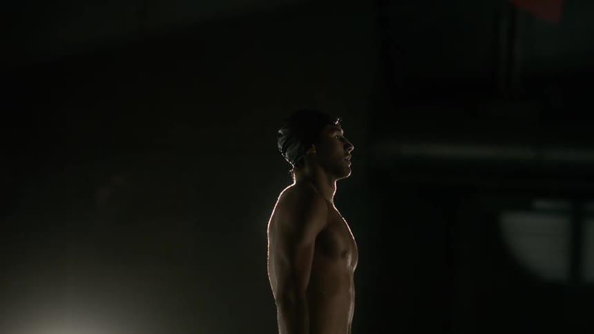 A swimmer is standing in a dark room