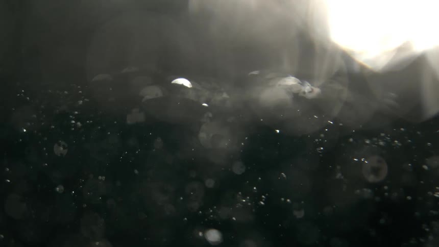 Close up of a person swimming in a pool with water and air bubbles