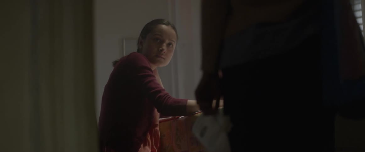 A girl is sitting down looking towards a person