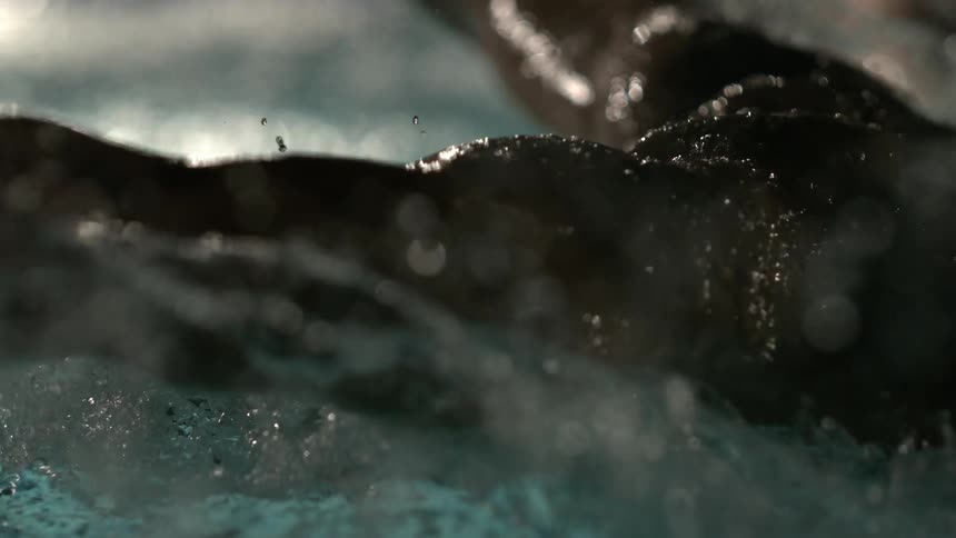 Close up of a male swimmer swimming in a pool with water flying
