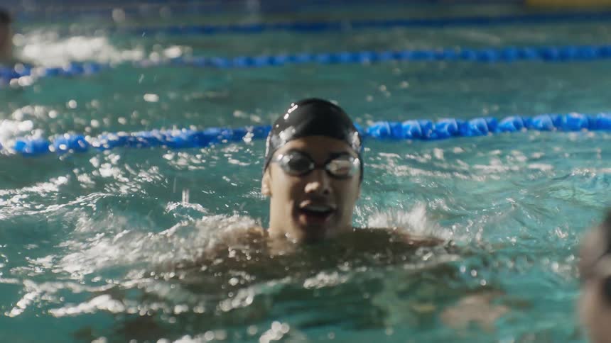 A swimmer propels through the pool winning the race and celebrating